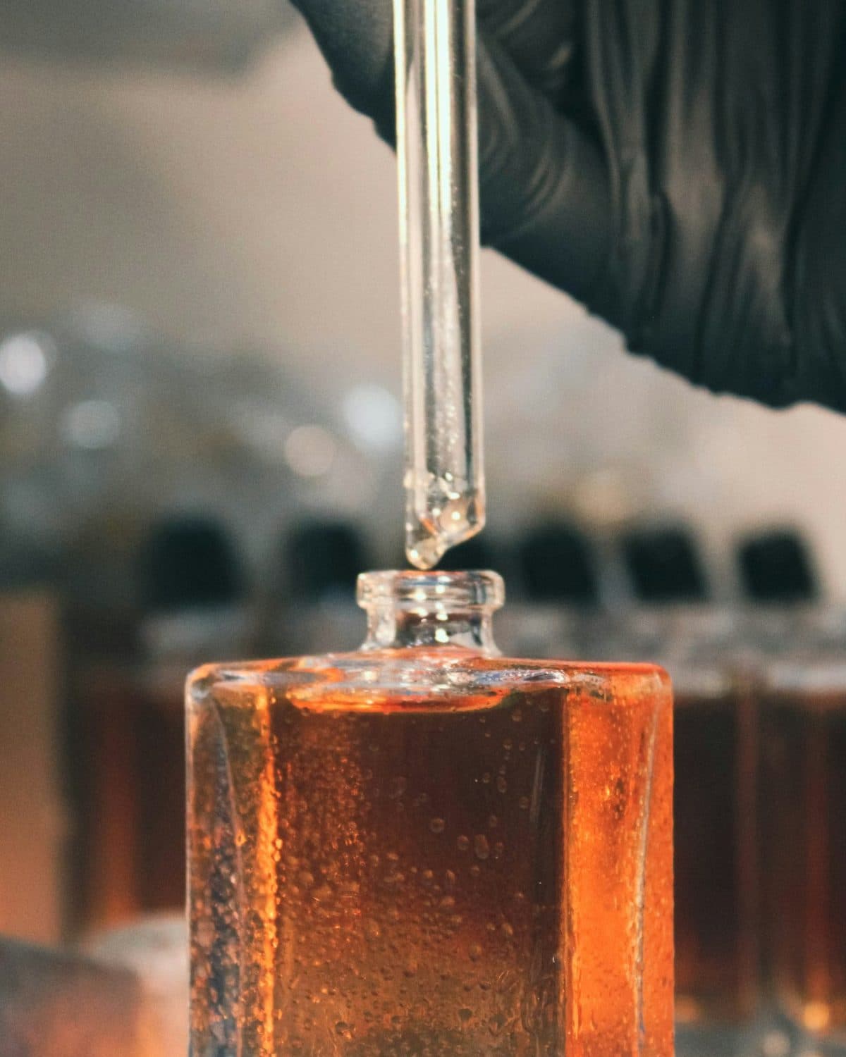 A gloved hand filling a glass flacon at the laboratory bench