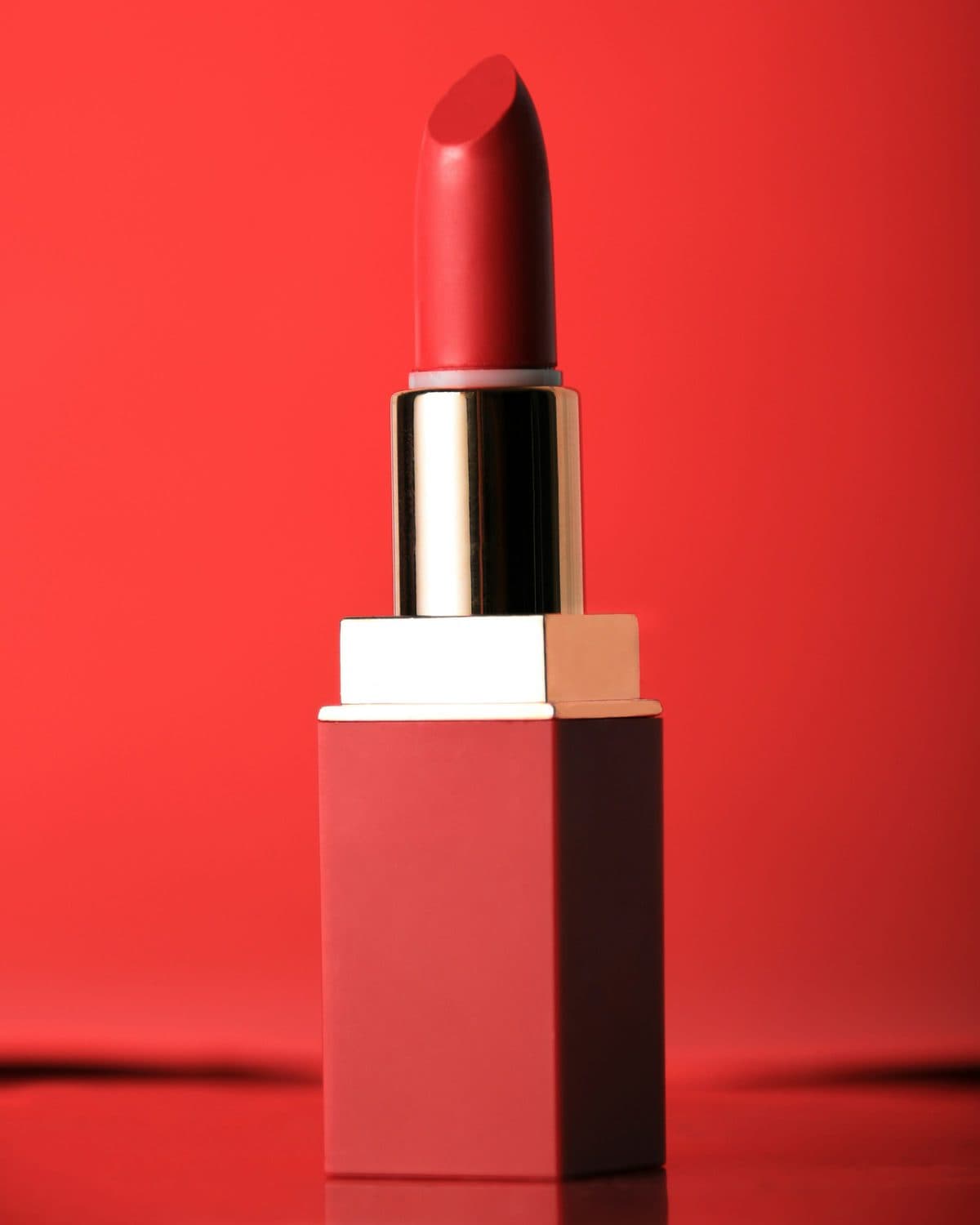A red lipstick standing on a red plinth