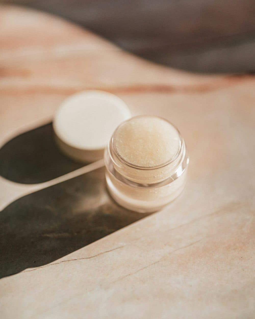 Baume Teinte open in its glass pot on pale marble